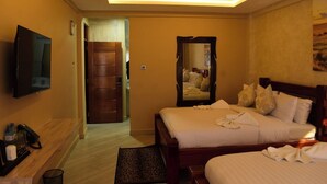 Une chambre d’hôtel avec un lit, une télévision, un bureau en bois et un miroir.