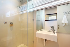 Un bagno moderno con cabina doccia in vetro, lavandino bianco e specchio.