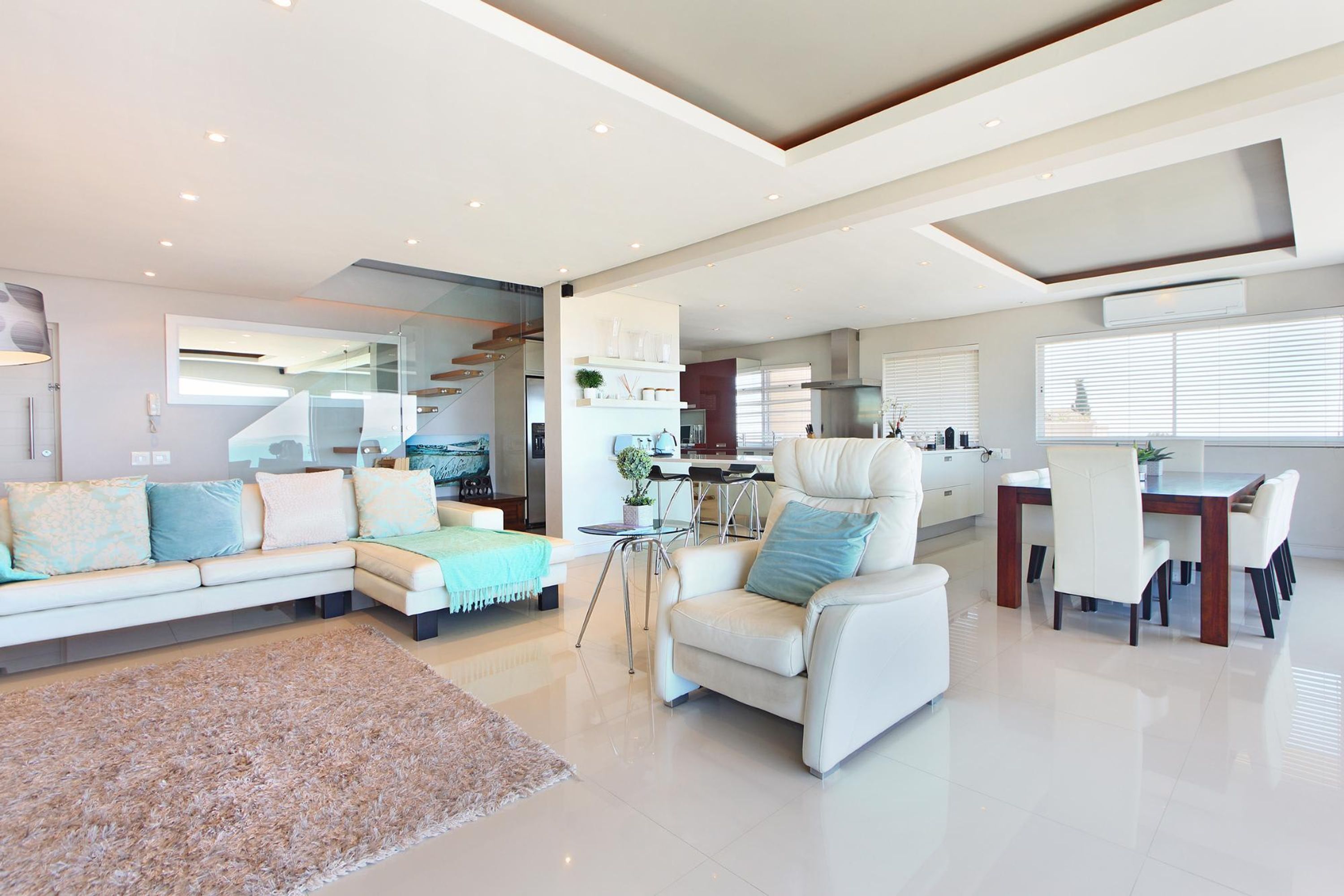 A spacious living area with a sofa, armchair, and dining table.
