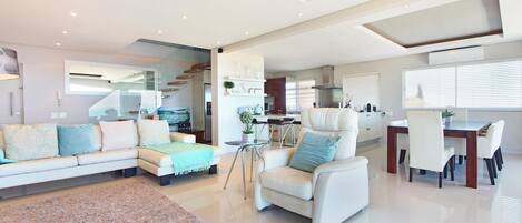 A spacious living area with a sofa, armchair, and dining table.