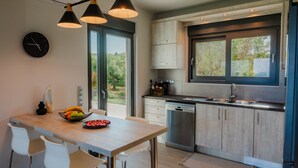 Una cocina moderna con una mesa de madera, sillas blancas y un ventanal amplio.