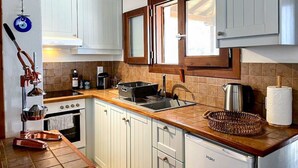A compact kitchen with white cabinets, a wooden countertop, a stove, and a dishwasher. - Pergamonto Cottage - Seaview Nest w Private Pool (Skopelos)