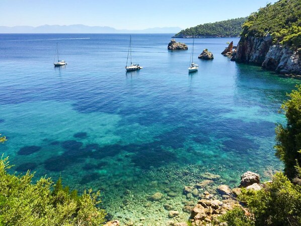 A coastal scene with clear water, boats, rocky outcrops, and greenery.