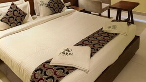 Una habitación de hotel con una cama grande, una silla, una mesita y un ventilador de techo.