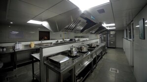 Una cocina comercial con electrodomésticos de acero inoxidable, una barra larga y una campana de ventilación.