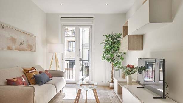 A modern living room with a sofa, a glass coffee table, a TV, and a balcony with a view. - Izpizua II | The Rentals Collection (San Sebastián/Donostia)