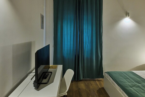 Una habitación de hotel pequeña y moderna, con escritorio, silla y cama.