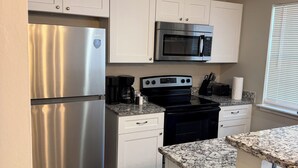 A kitchen with white cabinets, stainless steel appliances, granite countertops, and a window with blinds. - Charming 2-bedroom townhome with WiFi and AC in Charlotte University Area (Charlotte)