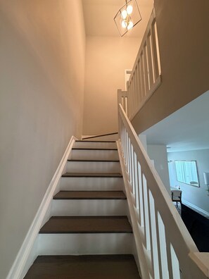 Un escalier avec des rampes blanches et un luminaire au sommet.