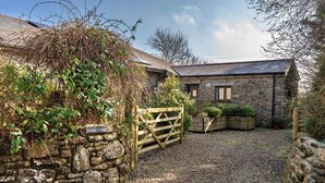 A stone cottage with a gravel driveway and a wooden gate. - Jubilee Barn Cottage at Bodmin Moor (St Breward)