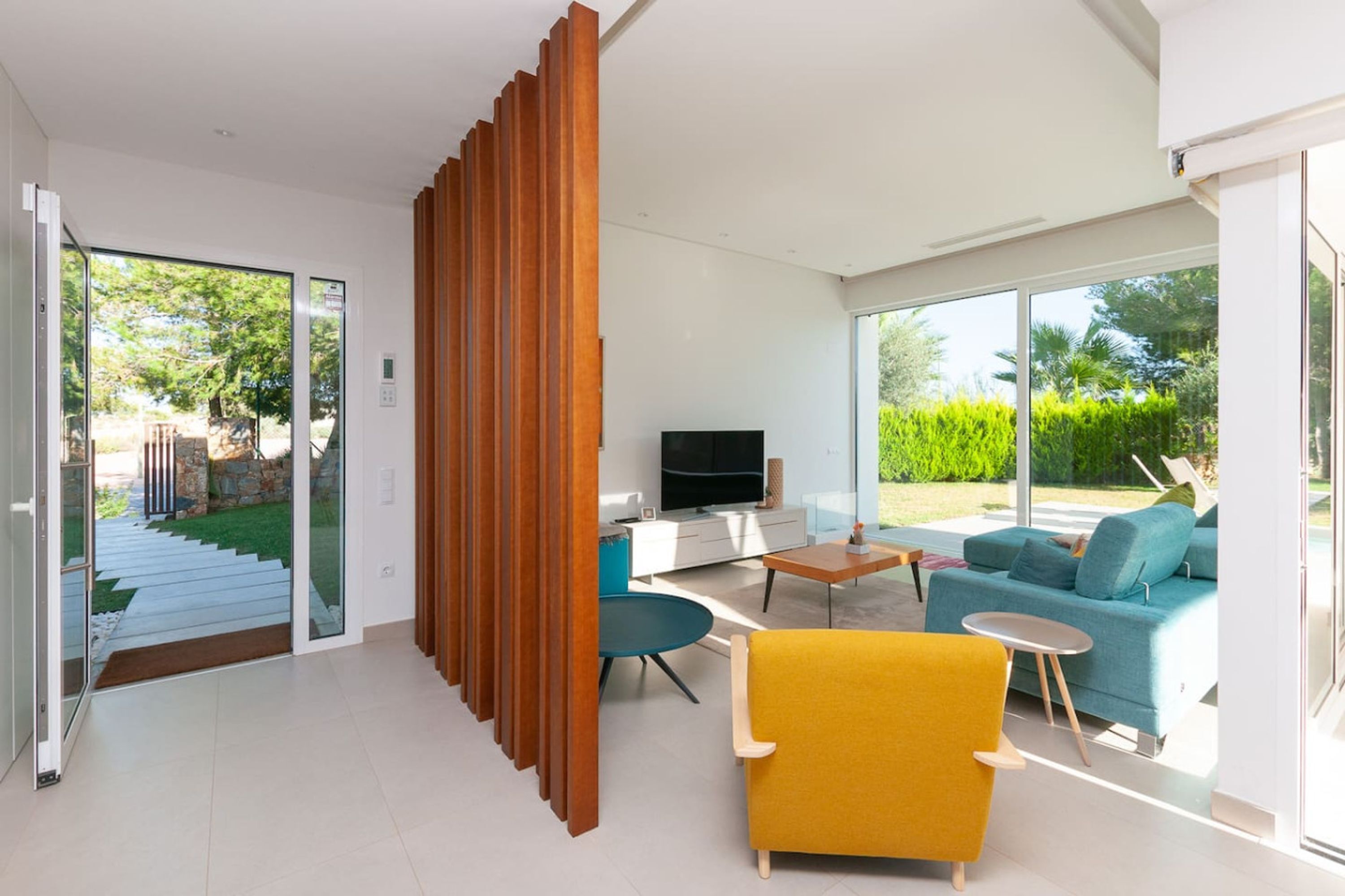 Uma sala de estar moderna com um sofá, uma poltrona amarela e uma televisão.