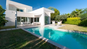 A modern two-story house with a swimming pool, outdoor seating, and lush greenery. - Sisu Willa z Podgrzewanym Basenem Las Colinas Golf (Orihuela)