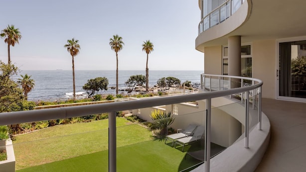 A modern building with a curved balcony overlooking a beach with palm trees and the ocean. - Bantry Place - Luxury Apartment (Cape Town)