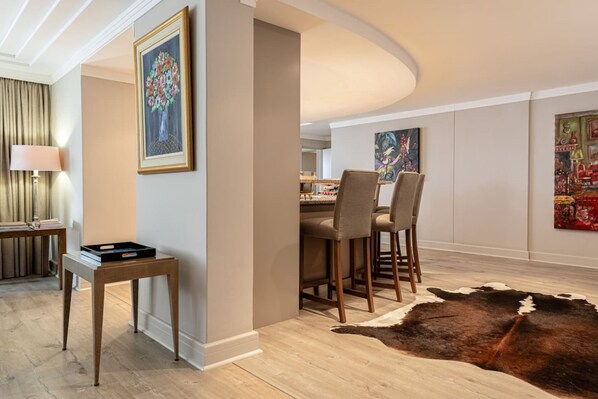Un espace de repas moderne avec une table et des chaises en bois, un tapis en peau de vache et des œuvres d’art encadrées accrochées aux murs.