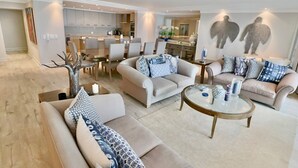 A modern living room with a sofa set, a coffee table, and a dining area with chairs and a table. - Bantry Place - Luxury Apartment (Cape Town)