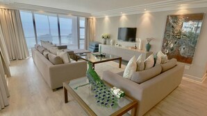 A modern living room with a sofa set, a coffee table, and a television. - Bantry Place - Luxury Apartment (Cape Town)