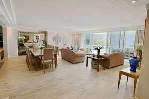 Een ruime woonkamer met een eethoek, banken en een salontafel.
