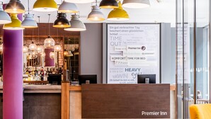 Zona de recepción de hotel con diseño moderno, mostrador de recepción y área de bar.