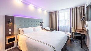 Una habitación de hotel con una cama grande, mesitas de noche, un escritorio y una silla.