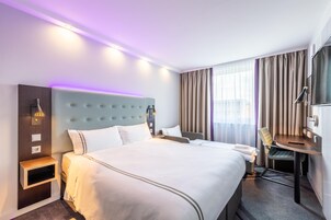 Ein Hotelzimmer mit einem großen Bett, Nachttischen, einem Schreibtisch und einem Stuhl.