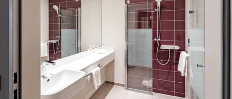 A modern bathroom with a glass-enclosed shower, a white sink, and a large mirror.