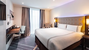 A hotel room with a large bed, a desk with a chair, a TV, and a window with curtains. - Premier Inn Frankfurt Messe (Frankfurt)