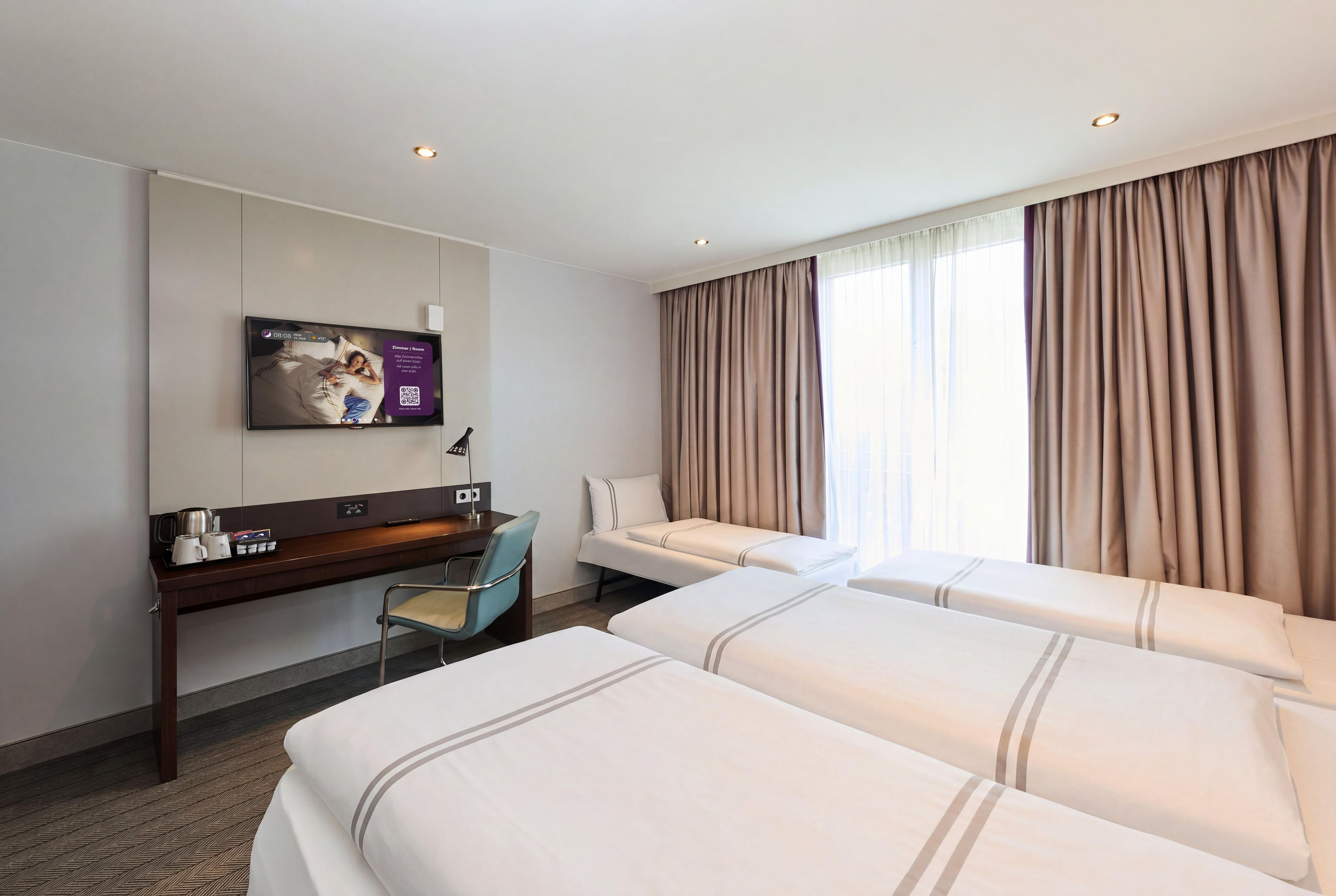 A hotel room with two beds, a desk, a chair, a television, and a window with curtains.
