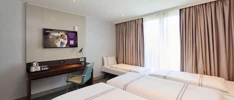 A hotel room with two beds, a desk, a chair, a television, and a window with curtains.