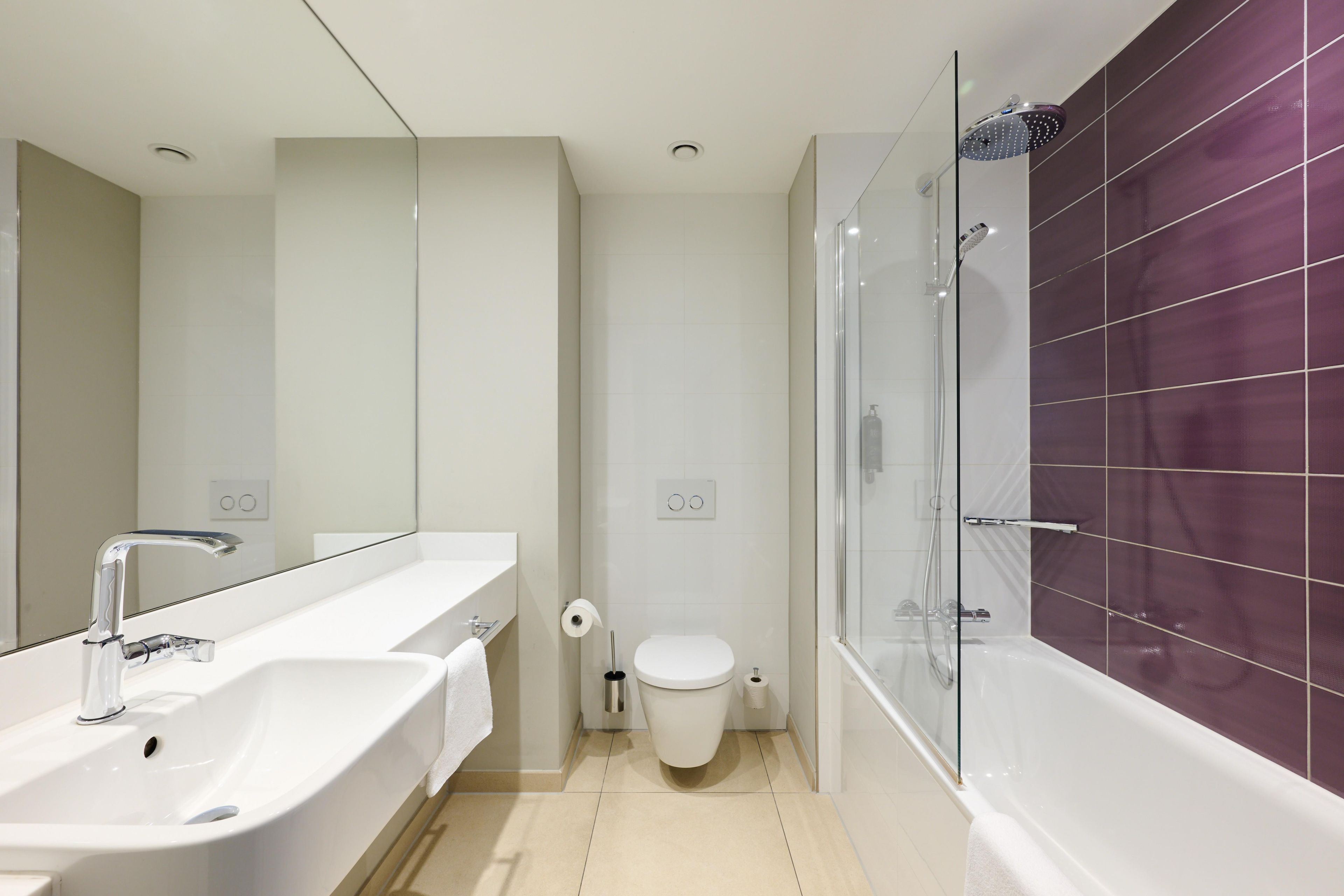 Une salle de bain moderne dotée d’un double lavabo, de toilettes et d’une douche à l’italienne.