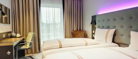 Habitación de hotel con cama, escritorio, silla y un amplio ventanal con cortinas.