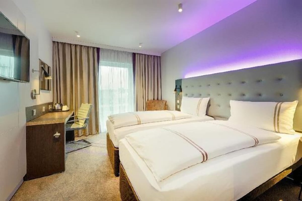 Ein Hotelzimmer mit zwei Betten, einem Schreibtisch, einem Stuhl und einem Fernseher.