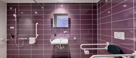Un baño moderno con ducha, lavamanos e inodoro accesible para sillas de ruedas.