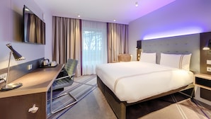 Una habitación de hotel con cama, escritorio, silla y televisor.