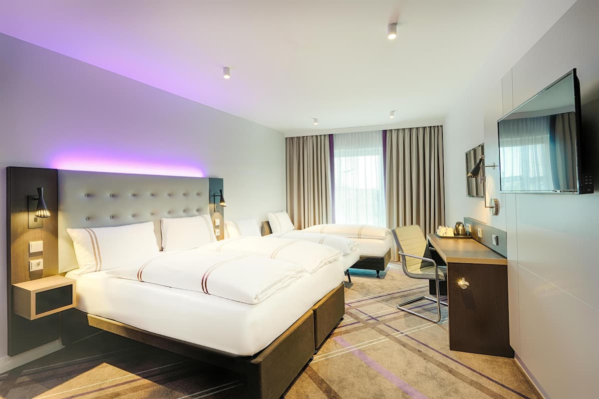 Una habitación de hotel moderna con una cama grande, un escritorio, una silla, un televisor y un baño.