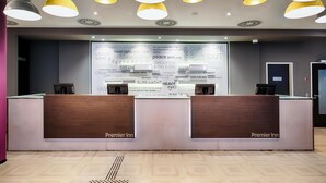 Un mostrador de recepción de hotel con diseño moderno, que cuenta con una barra de madera y múltiples lámparas colgantes.