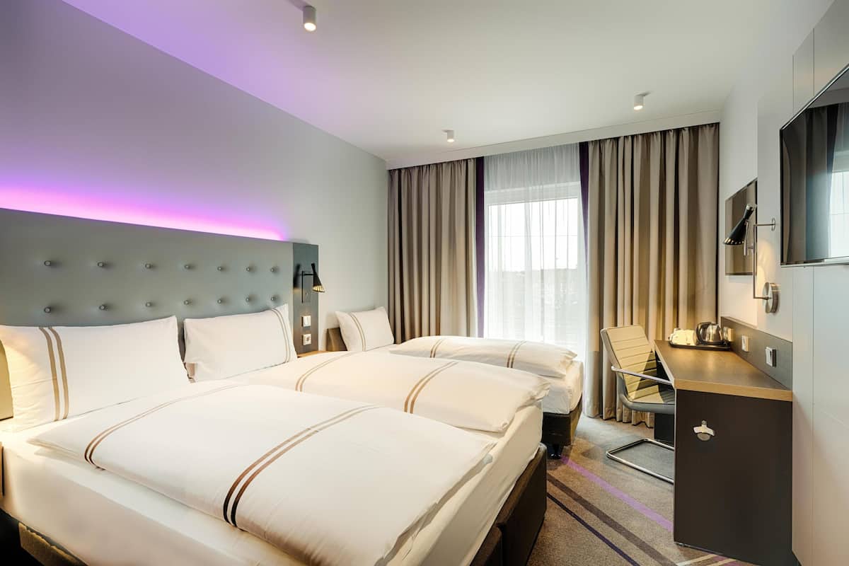 Habitación de hotel con una cama grande, un escritorio, una silla, un televisor y un minibar.
