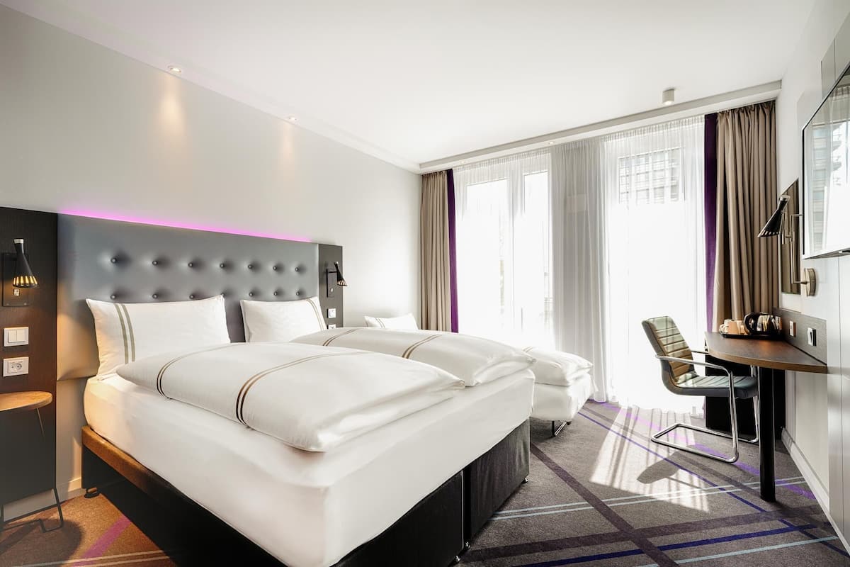 Una habitación de hotel con una cama grande, un escritorio, una silla y un televisor.
