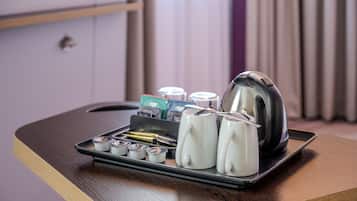 Un plateau avec un service à thé, comprenant une théière, des tasses et des morceaux de sucre, est posé sur une table en bois dans une chambre d’hôtel.