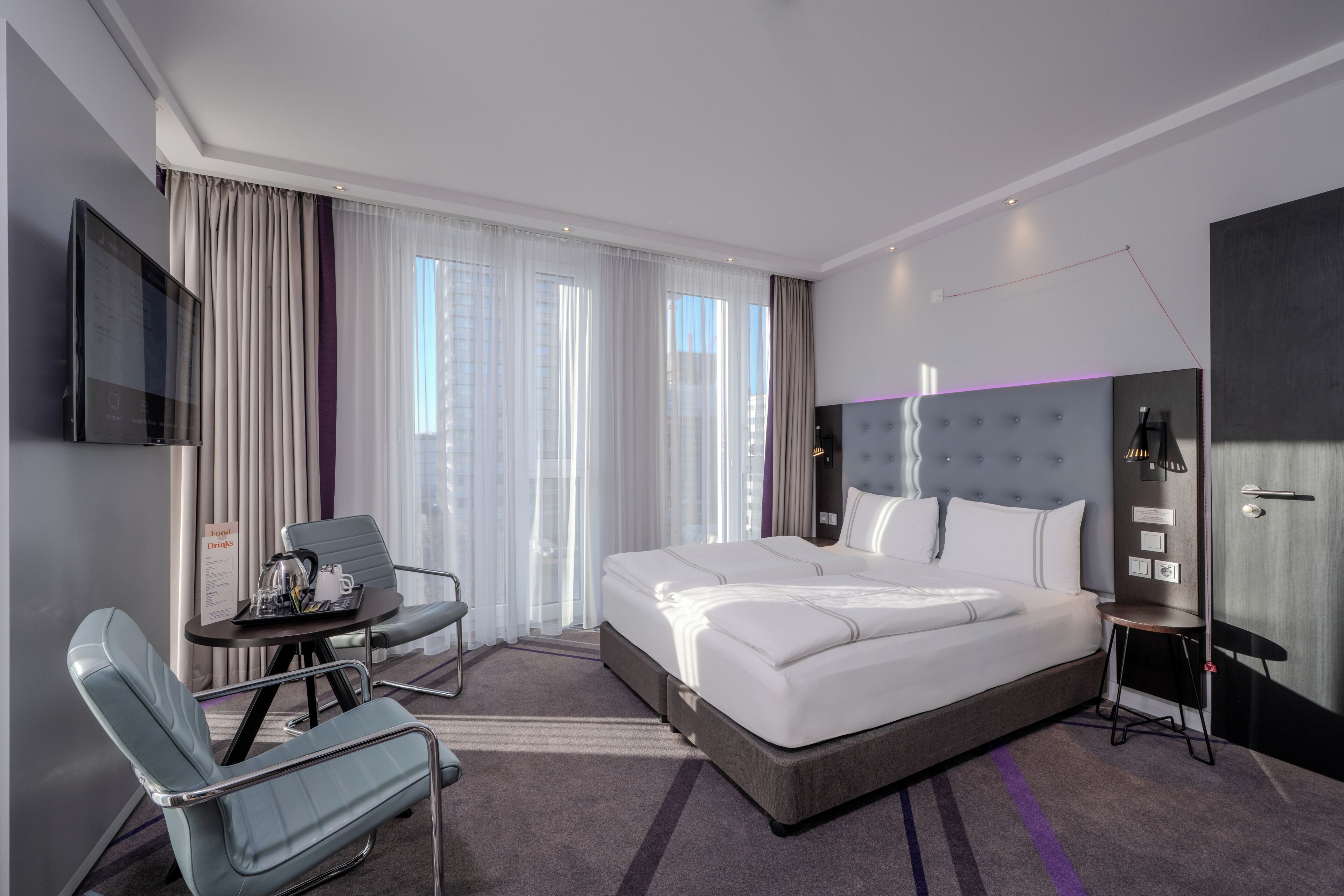 Ein modernes Hotelzimmer mit einem großen Bett, einem Schreibtisch, einem Stuhl und einem Fernseher.