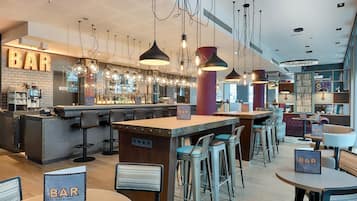 A bar area with multiple seating options, including bar stools and round tables, and a bar counter with a sign.