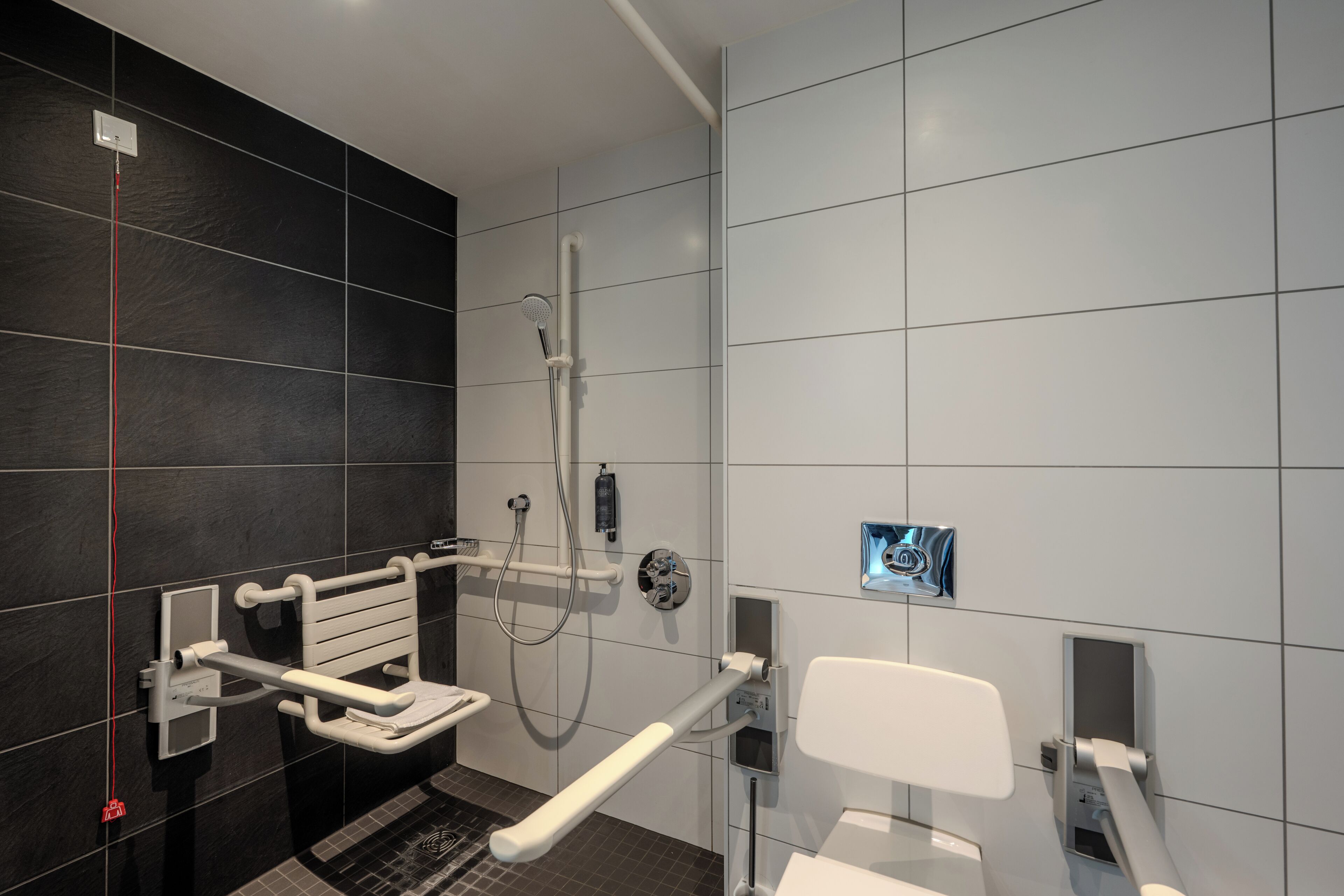A modern bathroom with a shower, toilet, and hand dryer.