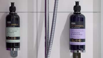 Dos recipients de bany de cos Goodness de Baylis & Harding sobre una paret de rajoles blanques.