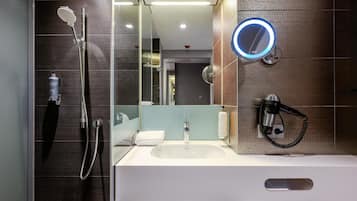 Un baño moderno con ducha, lavamanos, espejo y secador de pelo.