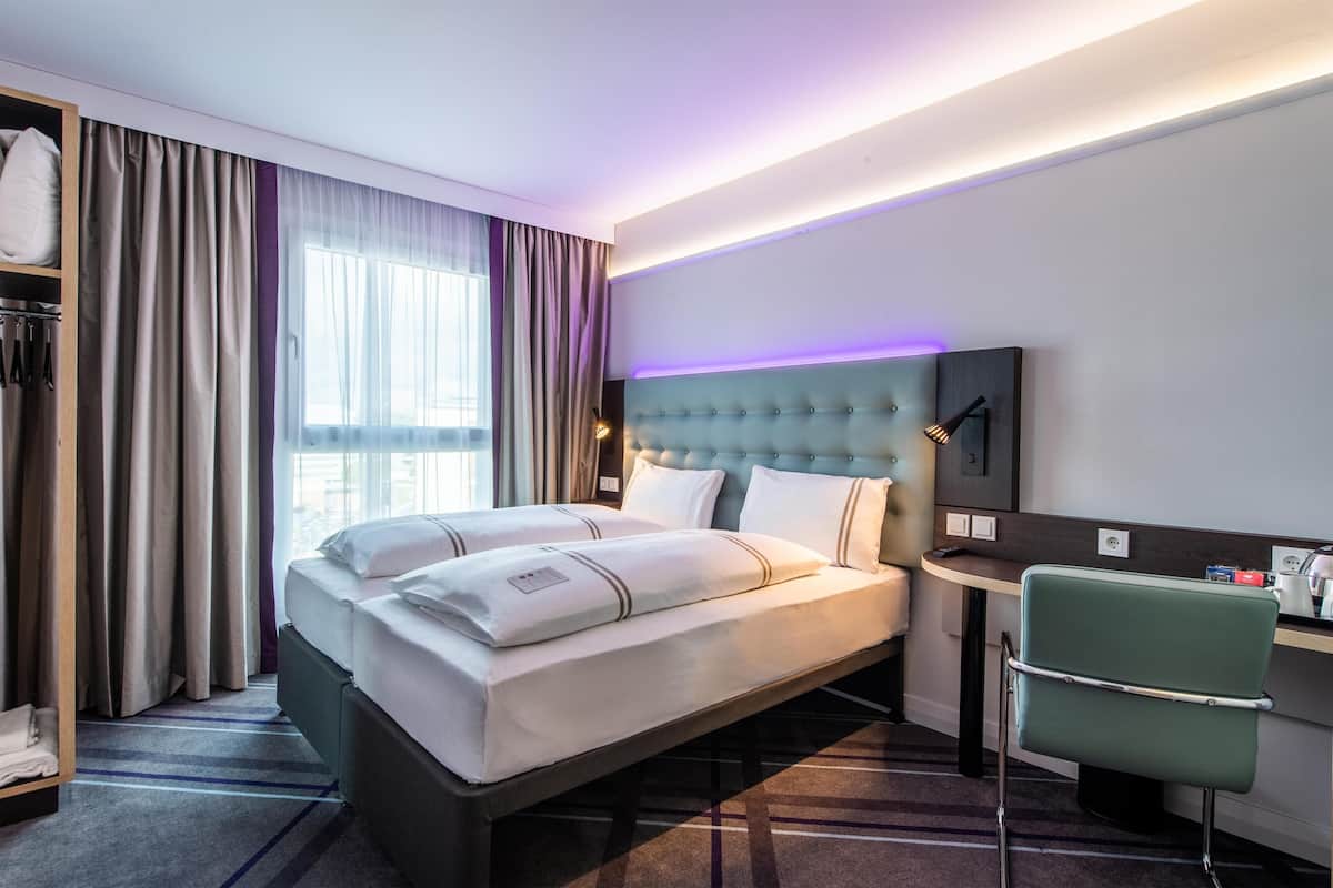 Una habitación de hotel con una cama grande, un escritorio, una silla y vistas a la ciudad.