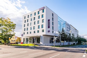 A modern hotel with a white facade, multiple windows, and a glass entrance.