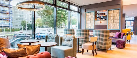 A modern interior with large windows, comfortable seating, and a visible bookshelf.