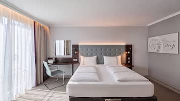 Ein Hotelzimmer mit Bett, Schreibtisch, Stuhl, Nachttisch und Wanduhr.