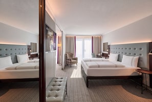 A hotel room with two beds, a sitting area, a desk, and a view of the outdoors. - Premier Inn Stuttgart Bad Cannstatt (Stuttgart)