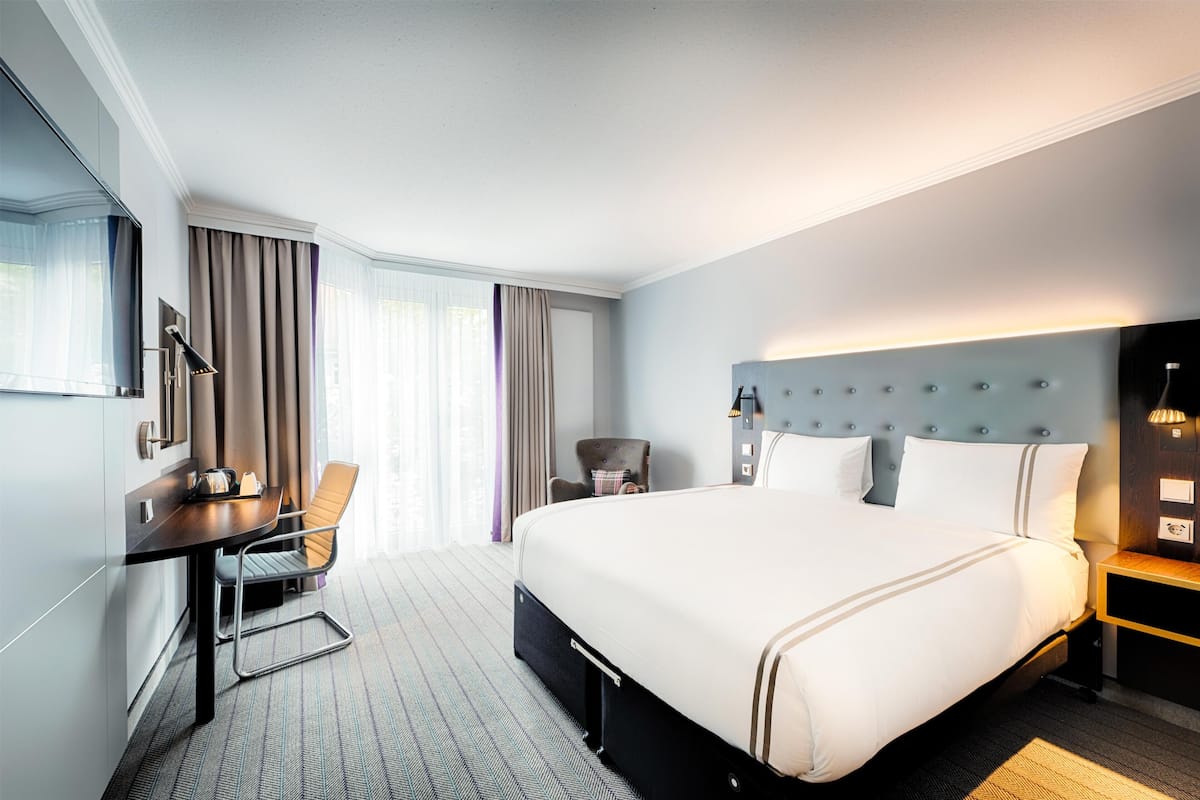 Una habitación de hotel con una cama grande, un escritorio, una silla y un televisor.