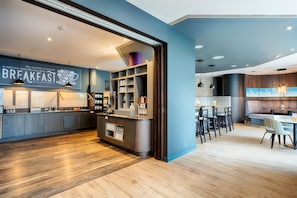 Un área de desayuno moderna con mostrador, asientos y una pared con un letrero alusivo al desayuno.